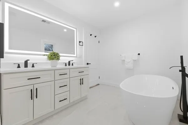 a bathroom with a tub sink and mirror