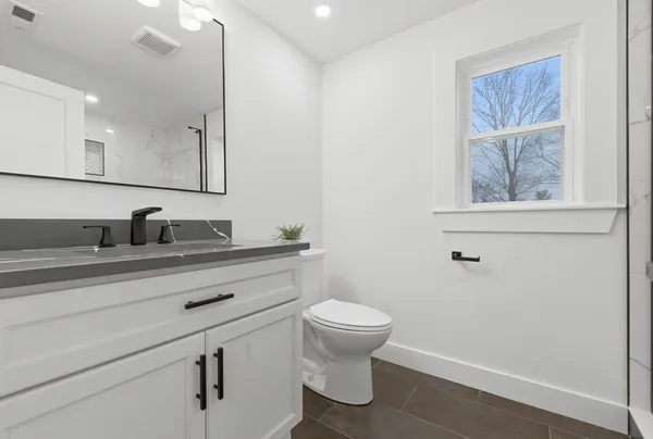 a bathroom with a granite countertop sink mirror vanity and toilet