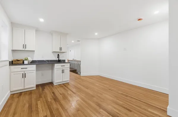 a kitchen with granite countertop white cabinets and wooden floor