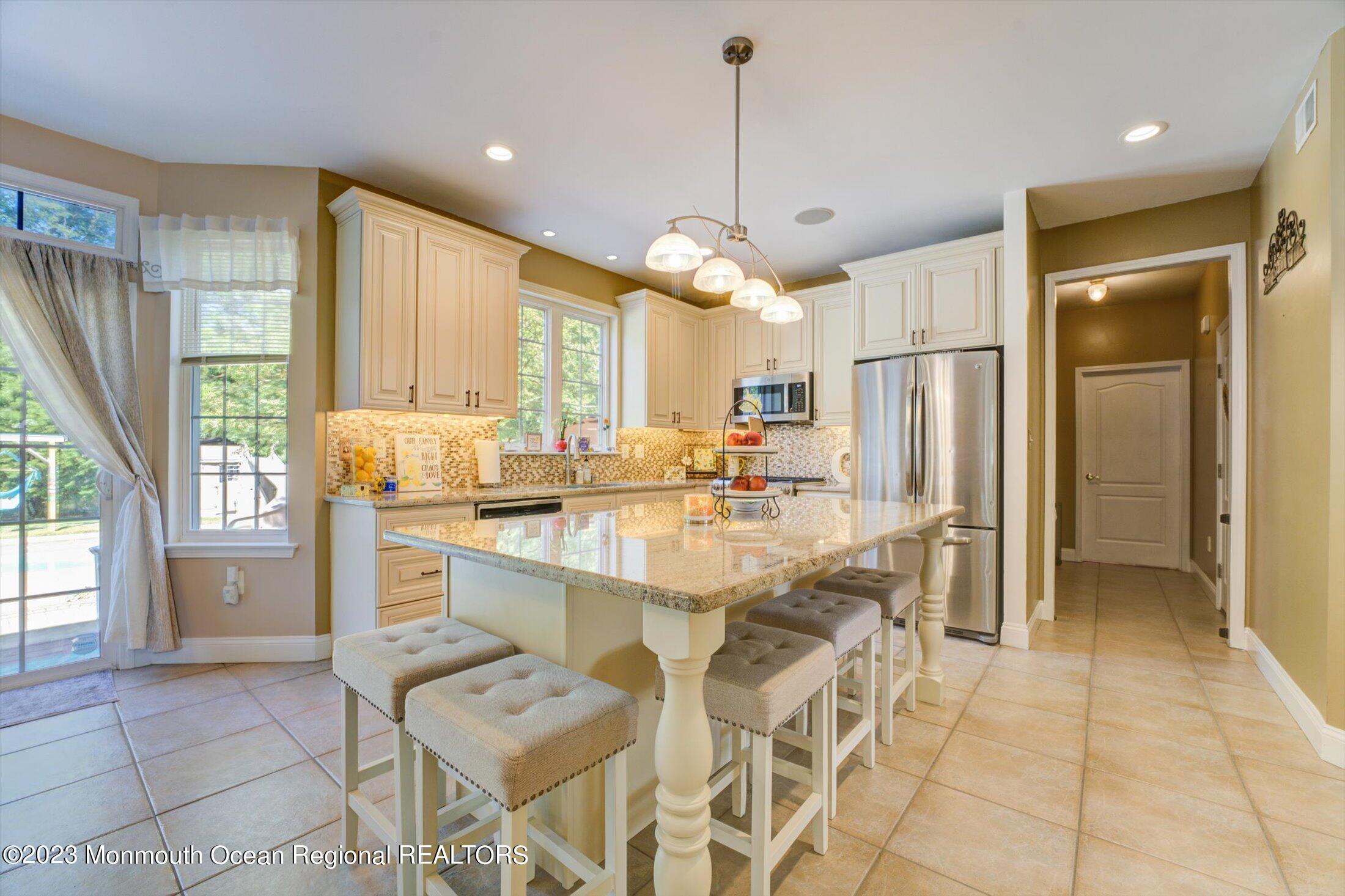 22 Rodeo Drive Jackson, NJ 08527 - Photo 4 of 42 a large kitchen with kitchen island granite countertop a refrigerator a stove a sink and a dining table with wooden floor