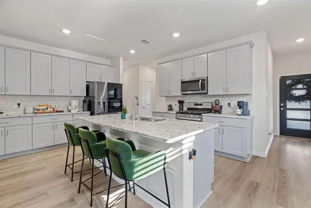 a kitchen with a sink a microwave a refrigerator and white cabinets