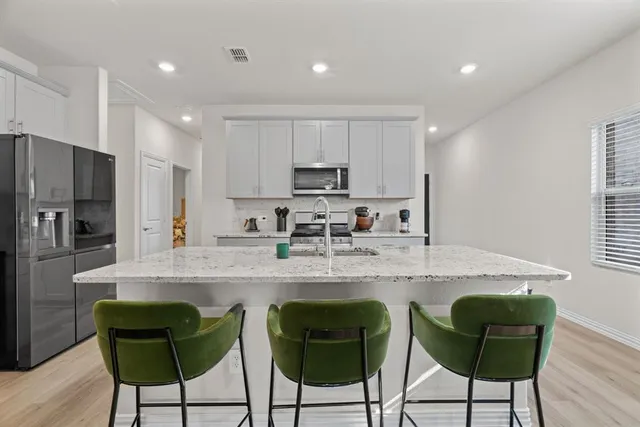 a kitchen with stainless steel appliances granite countertop a table and chairs in it