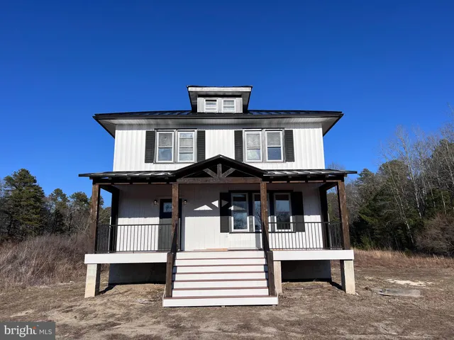 a white house that has tree in front of it
