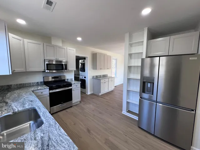 a kitchen with a refrigerator a stove top oven and wooden floor
