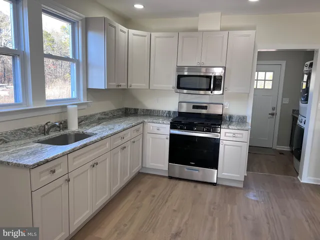 a kitchen with stainless steel appliances granite countertop a stove a sink and a microwave