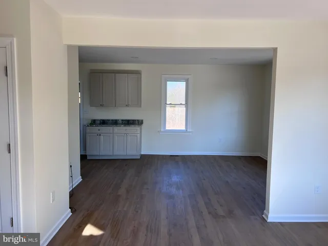 an empty room with wooden floor cabinet and windows
