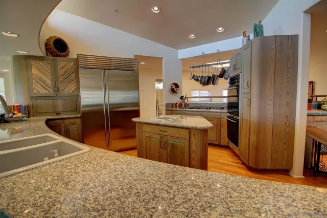 a kitchen with stainless steel appliances kitchen island granite countertop a refrigerator and a sink