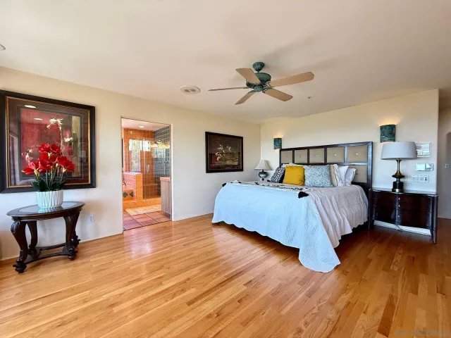 a bedroom with a bed and a large window with wooden floor