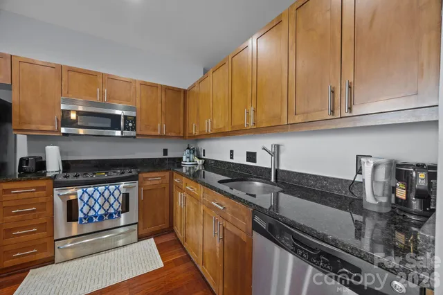 a kitchen with granite countertop a sink a stove and cabinets