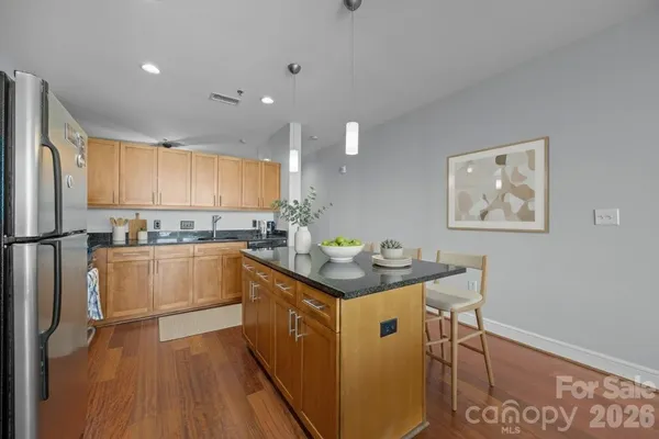 a kitchen with stainless steel appliances granite countertop a sink a stove a refrigerator a microwave oven with wooden floor and cabinets