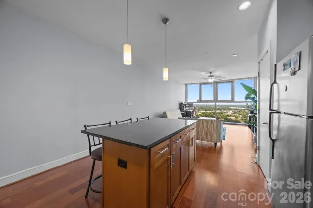 a kitchen with stainless steel appliances granite countertop a refrigerator a stove top oven a sink island and chairs