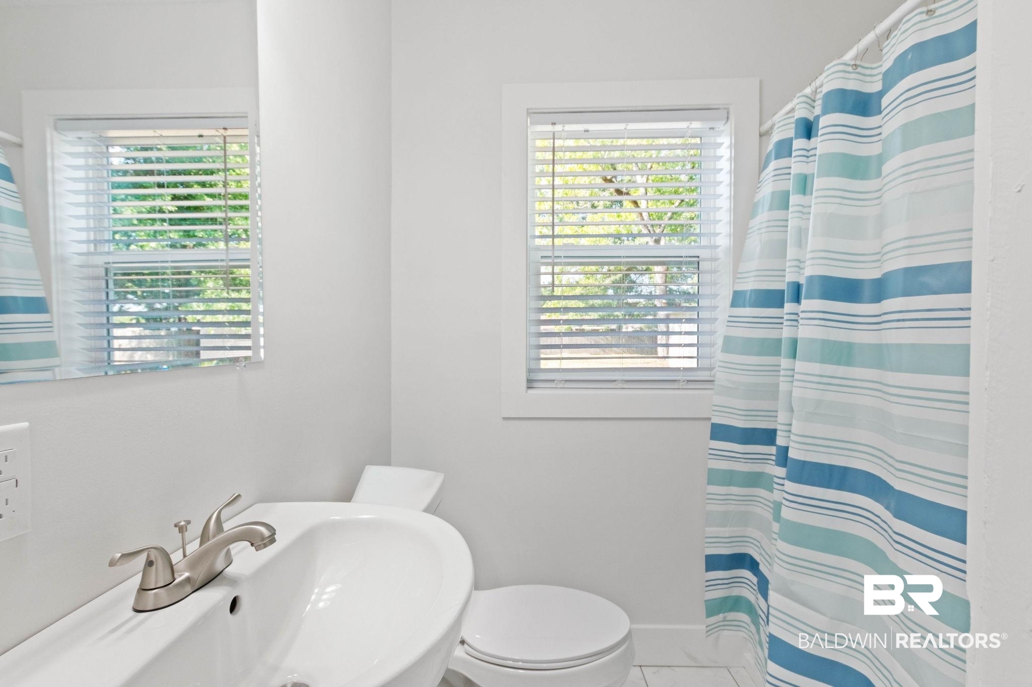311 Cloverdale Road Atmore, AL 36502 - Photo 41 of 63 Bathroom featuring a single window with blinds, a white pedestal sink, a two-piece toilet, and tiled flooring
