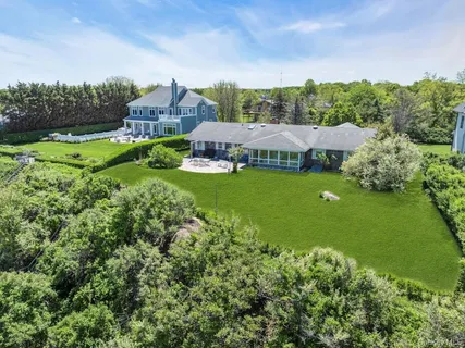 a view of a big house with a big yard and large trees