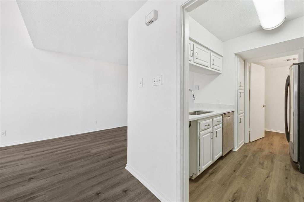 18240 Midway Road, Unit 402 Dallas, TX 75287 - Photo 23 of 29 Kitchenette featuring white cabinetry, a stainless steel sink with a chrome faucet, and integrated dishwasher