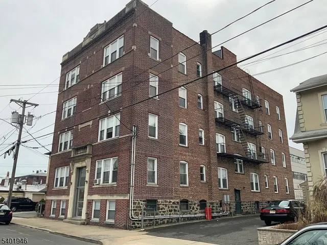 a front view of a building with lot of cars and trees