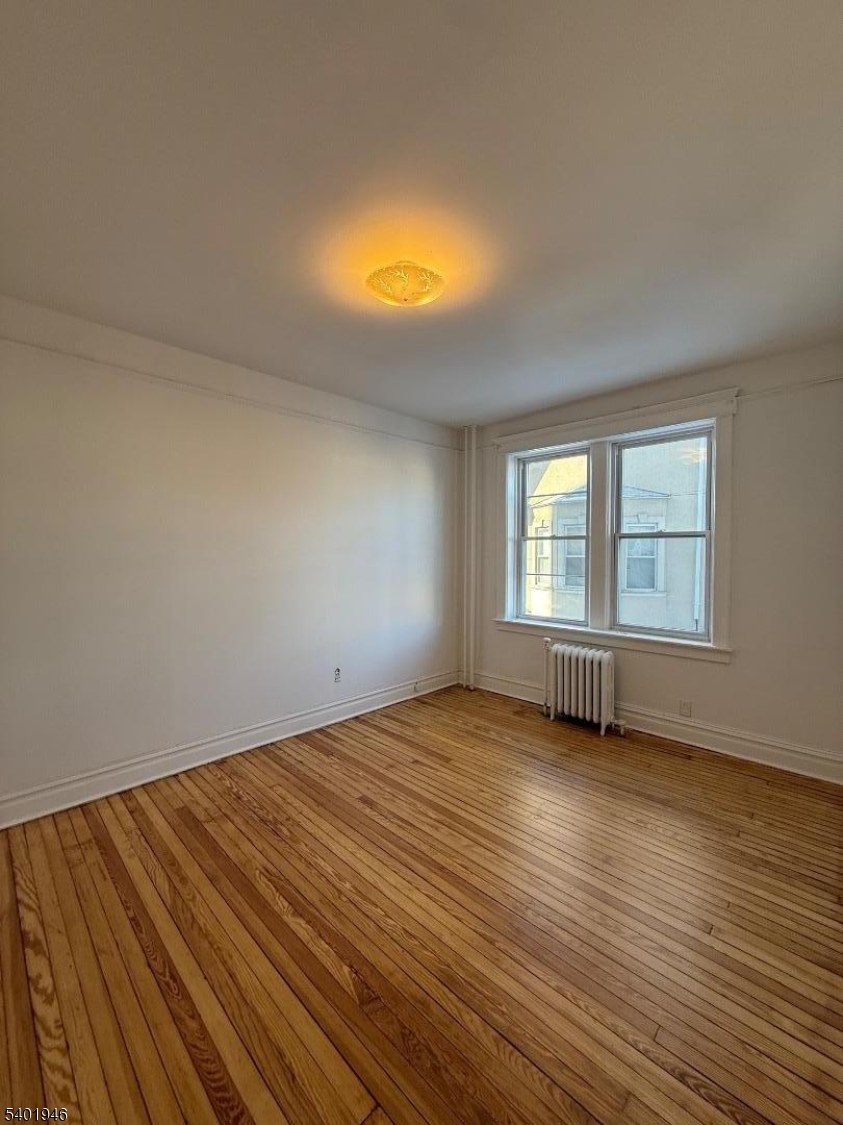 214 Lawton Avenue, Unit 1 Cliffside Park, NJ 07010 - Photo 2 of 6 a view of an empty room with wooden floor and a window