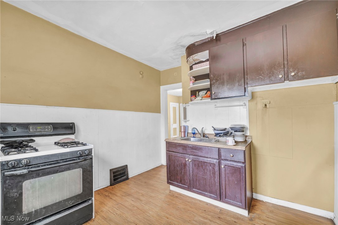 949 Rudyard Road Cleveland, OH 44110 - Photo 6 of 42 Kitchen featuring gas stove, open shelves, light wood finished floors, a wainscoted wall, and light countertops