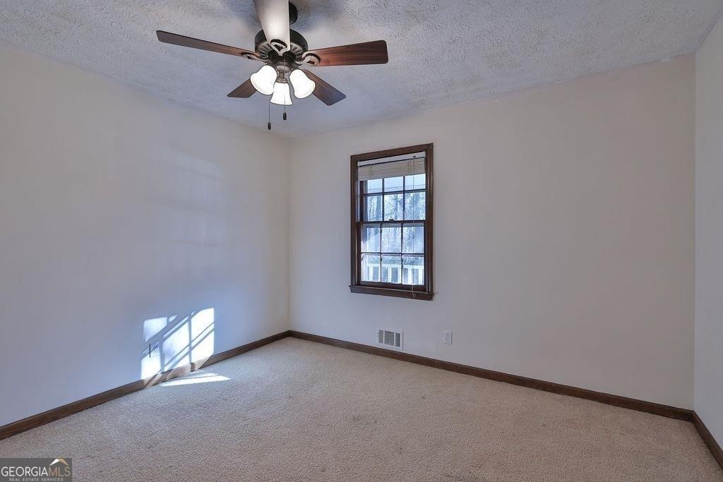 2733 Old Dawsonville Road Gainesville, GA 30506 - Photo 17 of 40 an empty room with a chandelier fan and windows