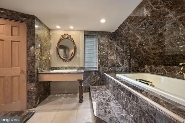 a spacious bathroom with a granite countertop sink and a bathtub