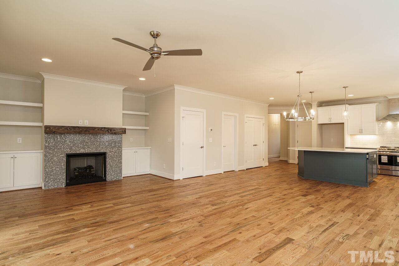 171 Adams Street Cary, NC 27513 - Photo 8 of 32 a view of kitchen and empty room with wooden floor and a fireplace