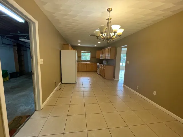 a view of a livingroom with a chandelier furniture and a kitchen view