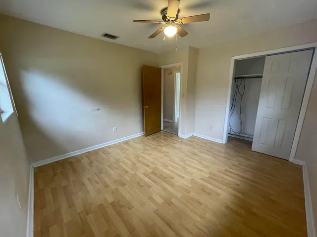 a view of empty room with wooden floor and fan