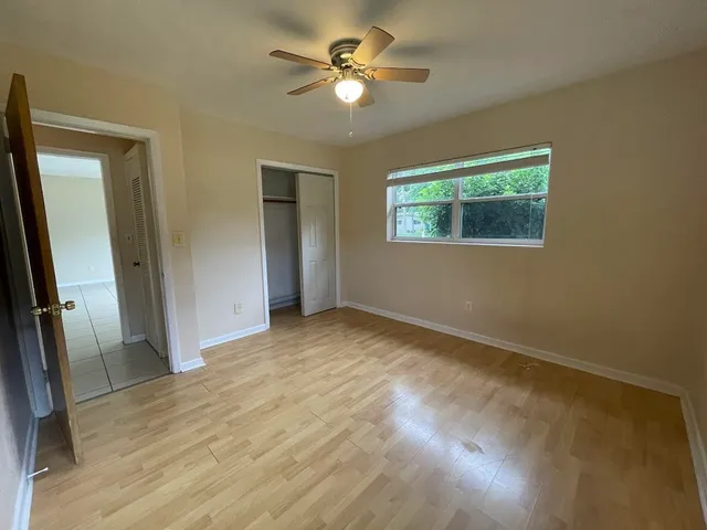 an empty room with closet and a ceiling fan