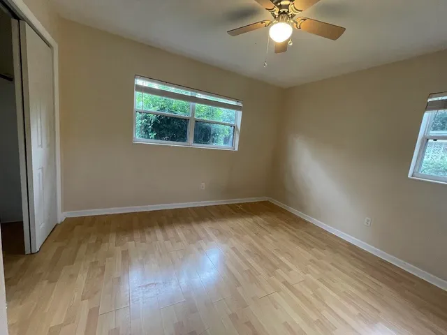 a view of an empty room with wooden floor and a window