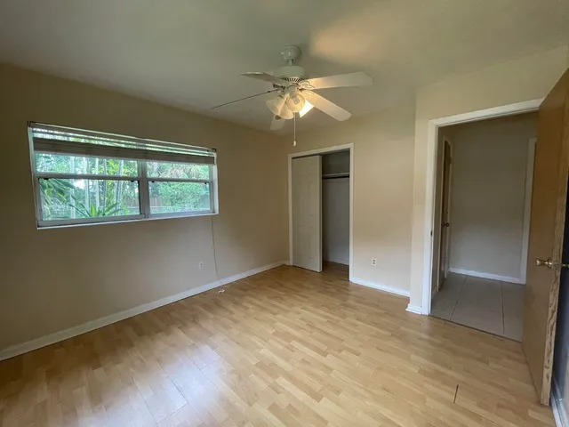 an empty room with wooden floor closet and windows