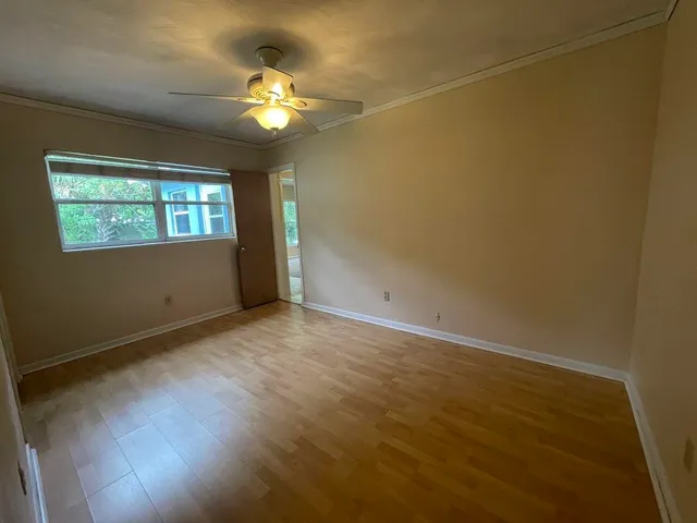 an empty room with a chandelier fan and windows