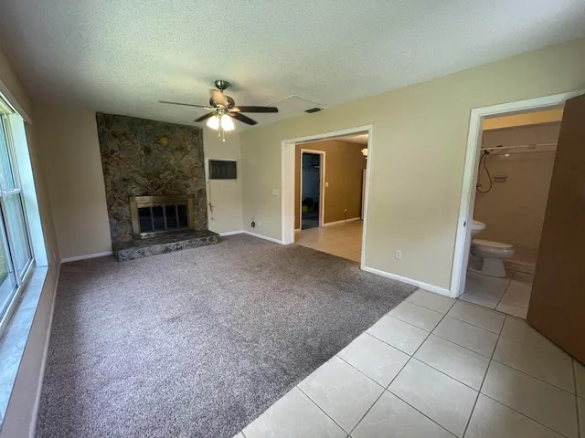 an empty room with fan and a fireplace