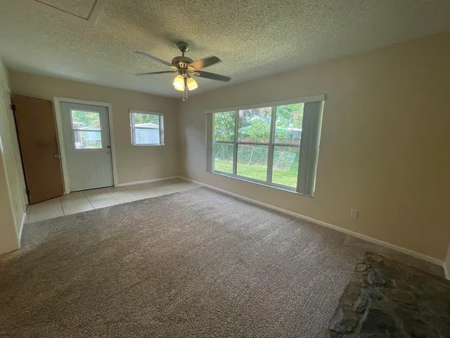 an empty room with windows and fan
