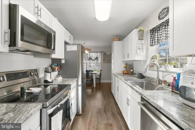 a kitchen with stainless steel appliances granite countertop a sink stove microwave and refrigerator