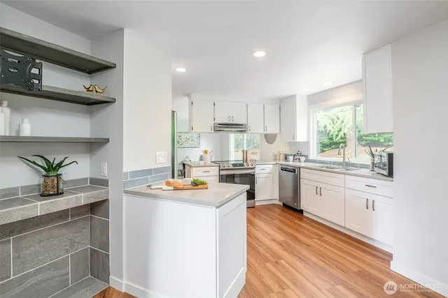 a kitchen with white cabinets and window