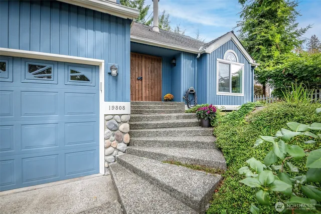 a view of a house with large windows and plants