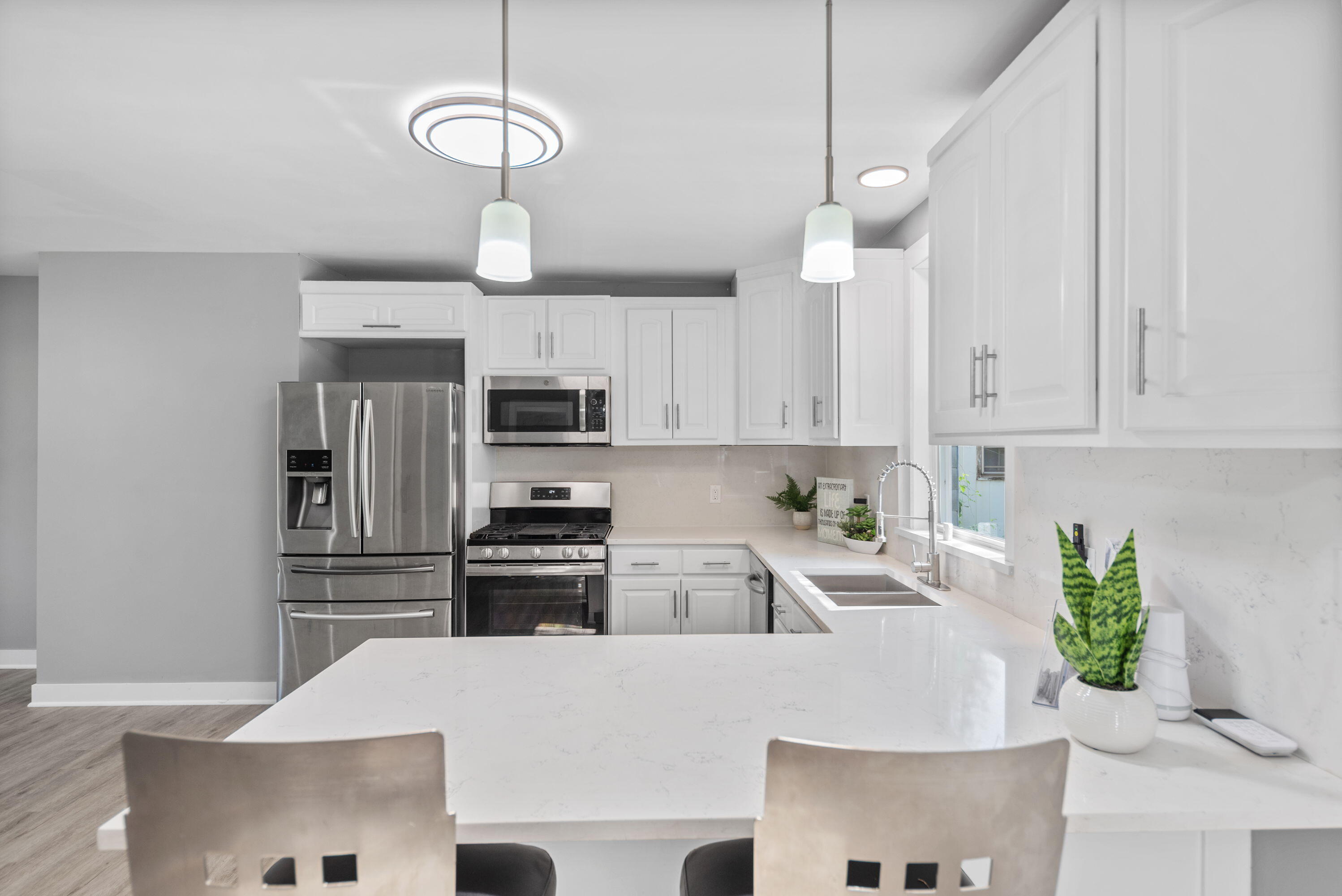 864 Ohio Street Gary, IN 46402 - Photo 7 of 27 a kitchen with stainless steel appliances granite countertop a refrigerator a stove a sink dishwasher and white cabinets with wooden floor