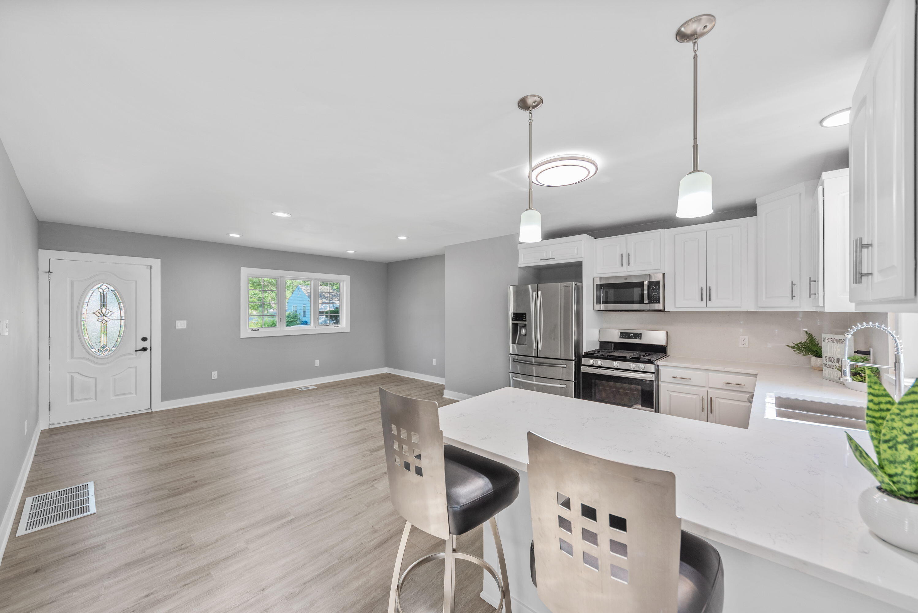 864 Ohio Street Gary, IN 46402 - Photo 8 of 27 a kitchen with stainless steel appliances kitchen island granite countertop a stove a sink a oven a dining table and chairs with wooden floor