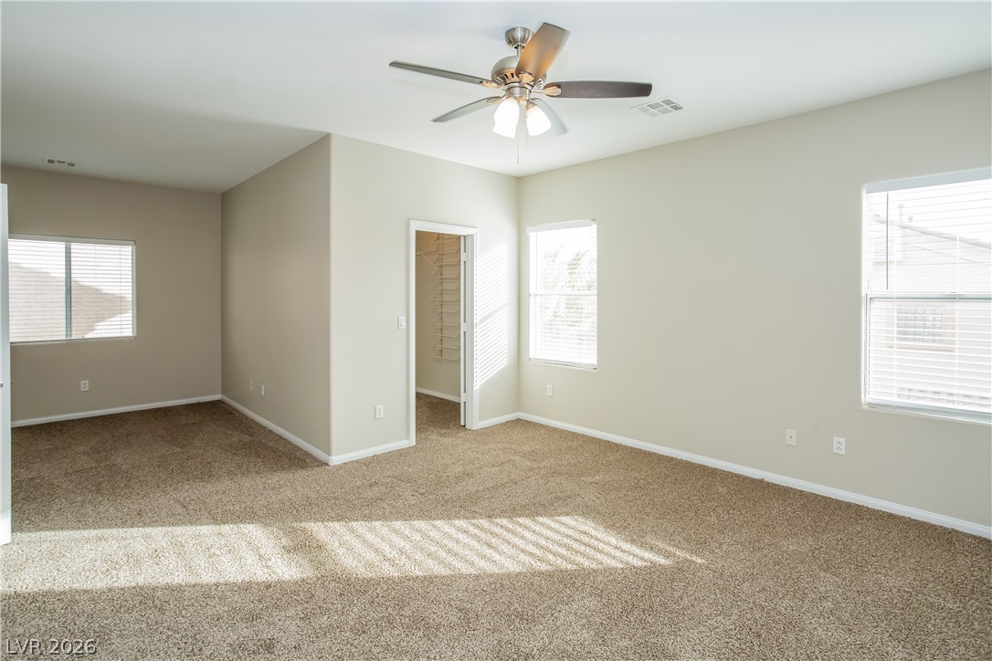 7630 Riva Ridge Street Las Vegas, NV 89149 - Photo 5 of 14 Sunlight filters across the carpeted flooring of this primary bedroom suite with an attached closet.