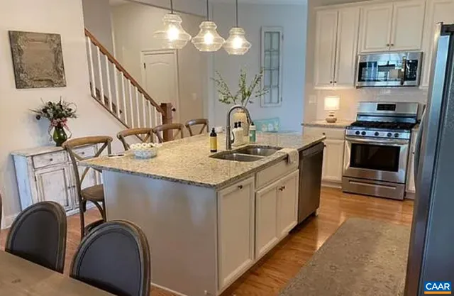 a kitchen with kitchen island granite countertop a sink cabinets and stainless steel appliances