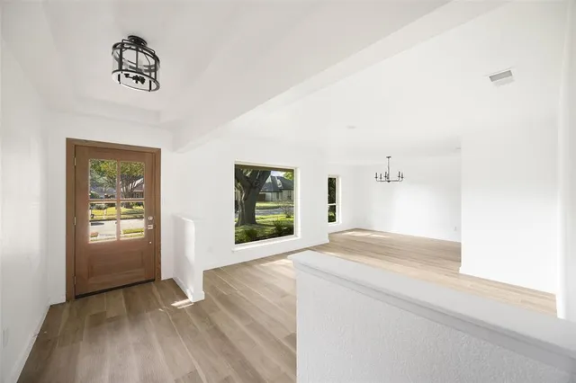 a view of an empty room with window and wooden floor