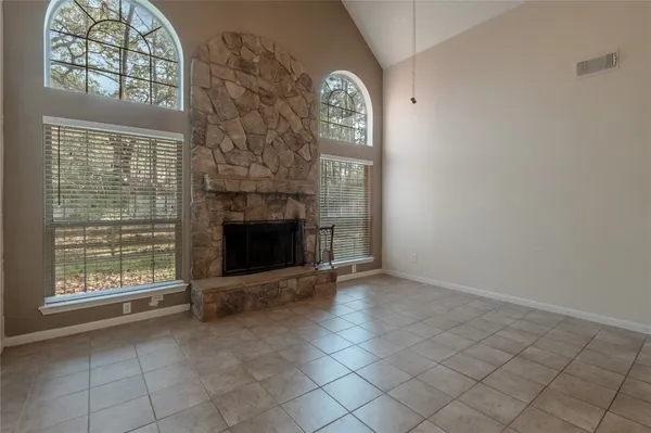an empty room with windows fireplace and fans