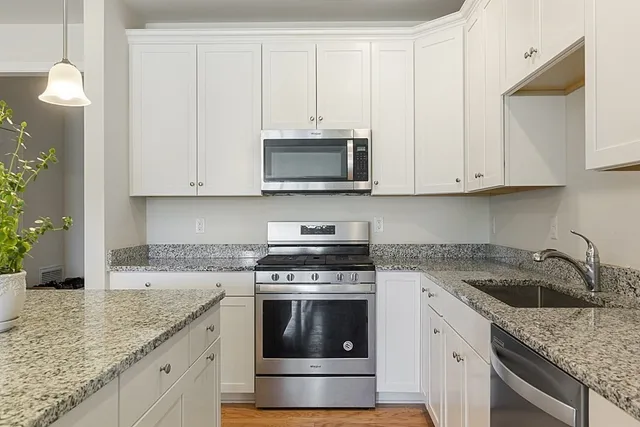 a kitchen with granite countertop white cabinets and a stove a oven with white countertops