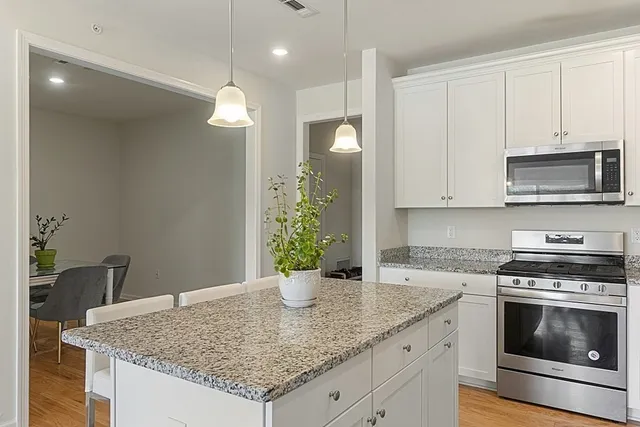 a kitchen with stainless steel appliances granite countertop a sink a stove and cabinets