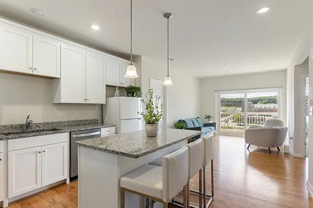 a open kitchen with granite countertop a stove a sink a center island and wooden floor