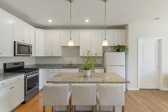 a kitchen with kitchen island granite countertop a stove a sink a kitchen island with a dining table and chairs