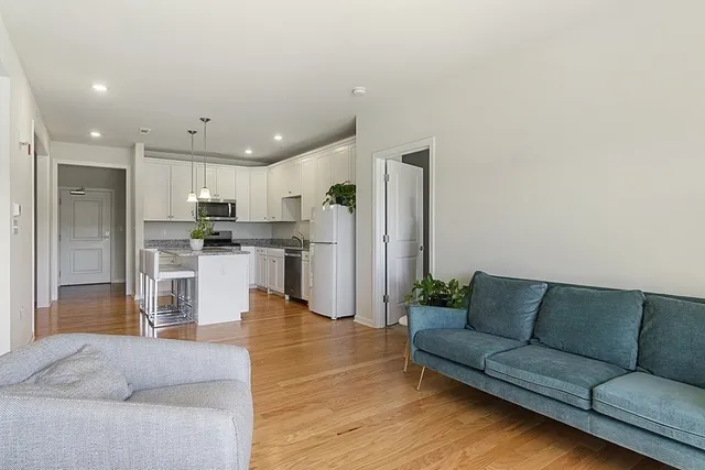 a living room with stainless steel appliances kitchen island granite countertop a couch and a view of living room