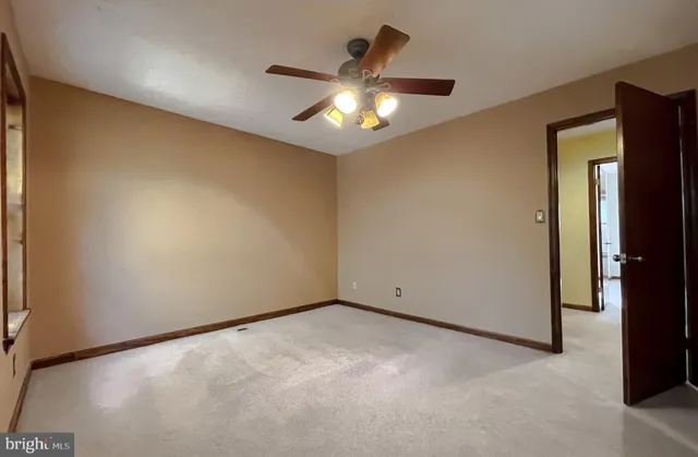 an empty room with a ceiling fan and a window