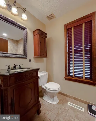 a bathroom with a toilet a sink a mirror and a window