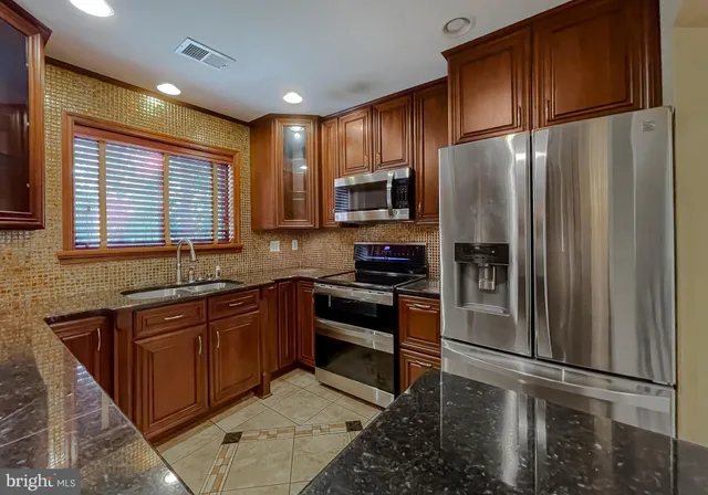 a kitchen with stainless steel appliances granite countertop a refrigerator a stove a sink and a microwave