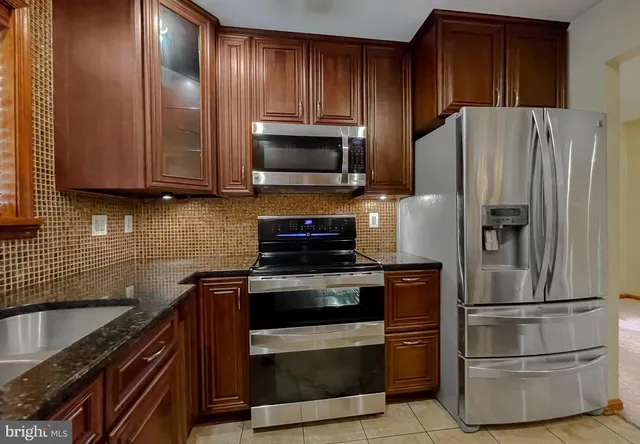 a kitchen with granite countertop wooden cabinets and stainless steel appliances
